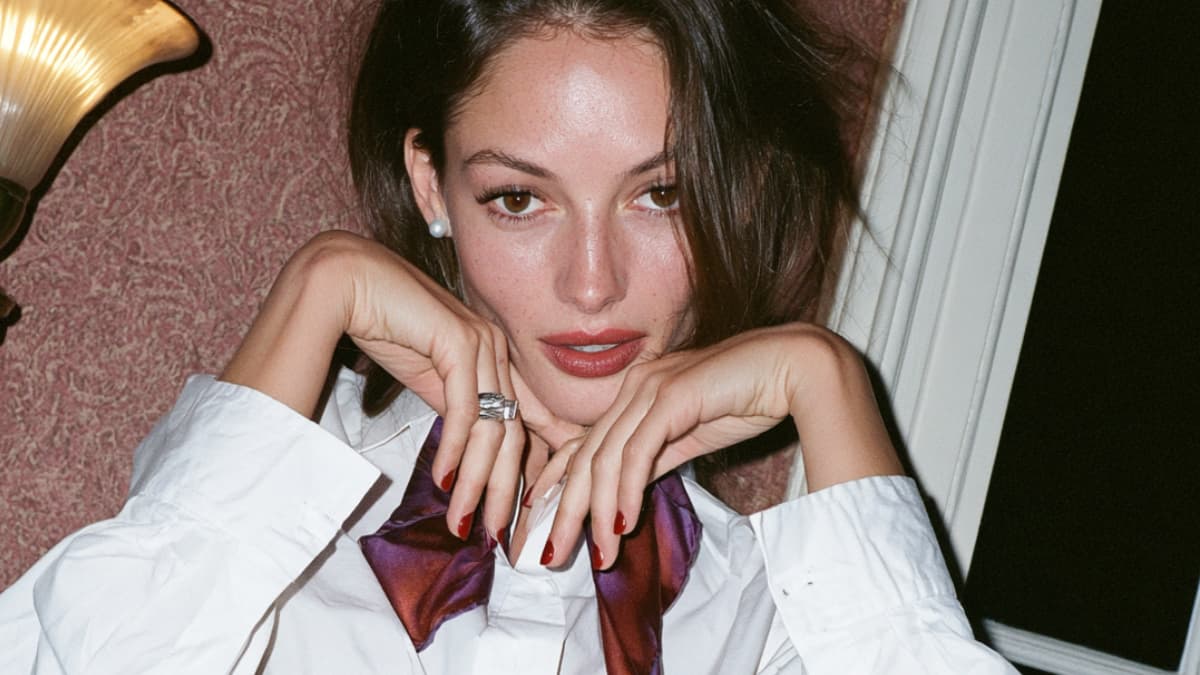 Elegant portrait of a woman in a white shirt and purple satin bow tie with a confident, defined gaze. Conceptual image for Facial Threading services, a precise facial and eyebrow threading technique that enhances your natural features while leaving your skin smooth, clean, and beautifully defined.